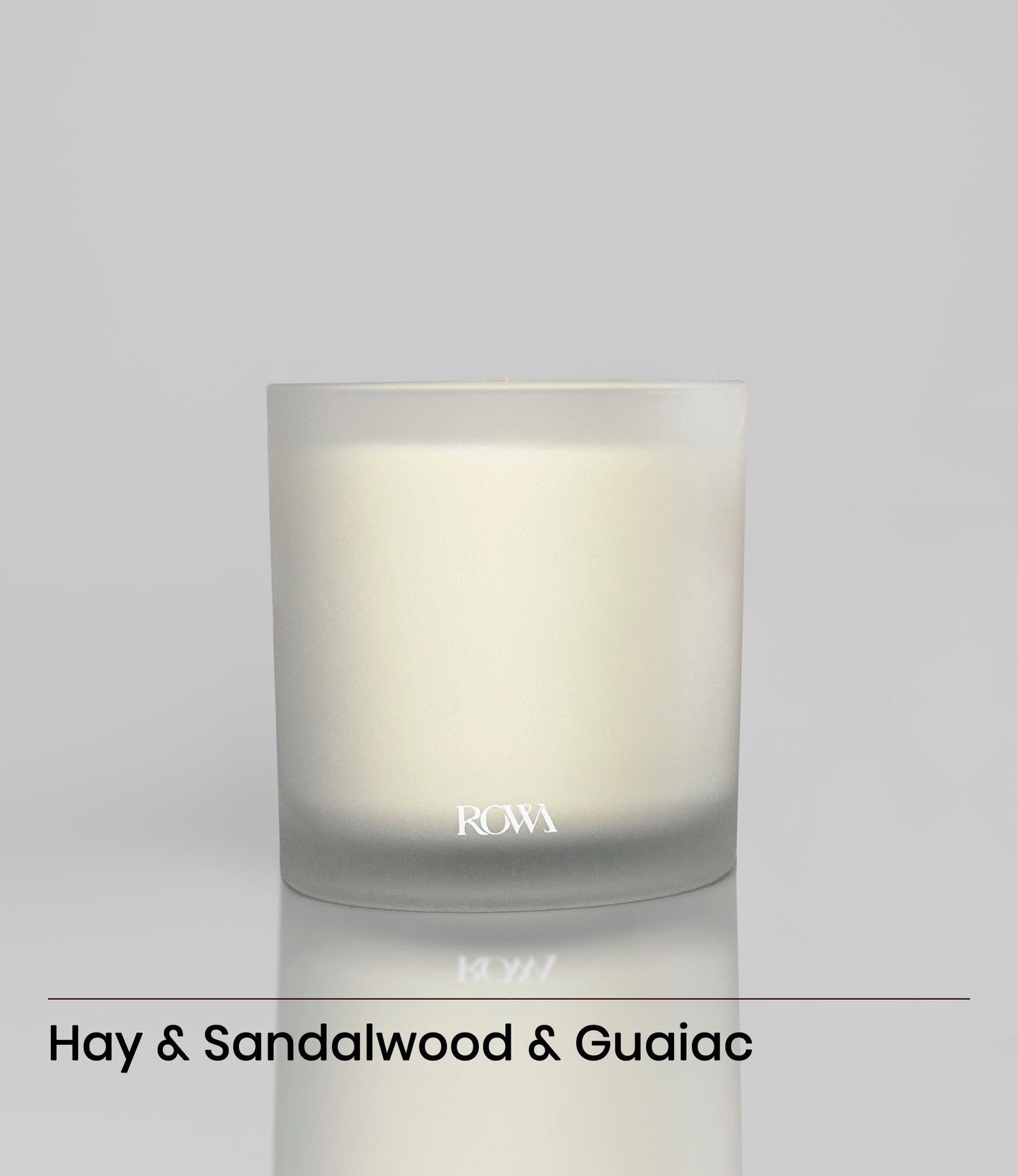 ROWA Pine Tree candle in frosted glass, styled with greenery and dark wood to evoke a grounding forest atmosphere with bamboo and leather notes.