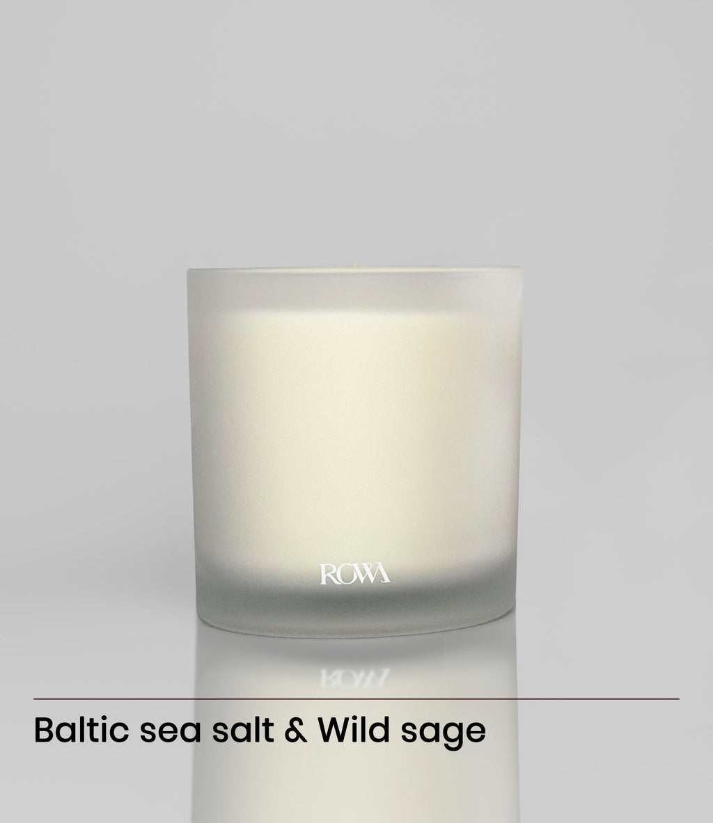 ROWA Miles candle in frosted glass, styled with coastal tones and summer light to reflect its ocean-inspired scent of sea salt and sage.
