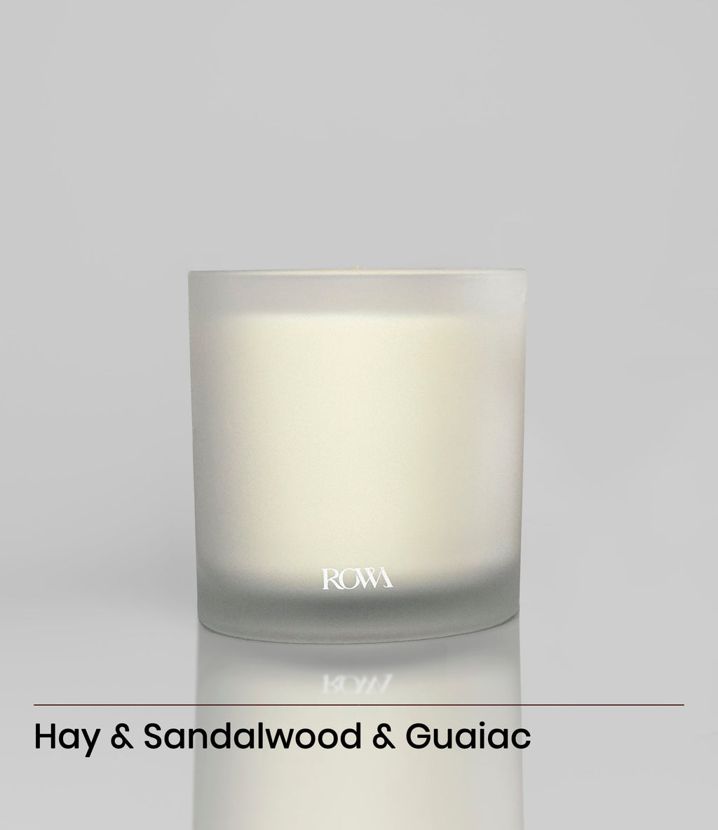 ROWA Pine Tree candle in frosted glass, styled with greenery and dark wood to evoke a grounding forest atmosphere with bamboo and leather notes.
