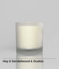 ROWA Pine Tree candle in frosted glass, styled with greenery and dark wood to evoke a grounding forest atmosphere with bamboo and leather notes.
